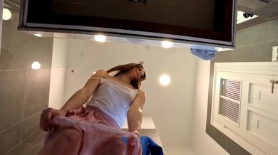 Ragazza bruna magra e arrapata senza reggiseno in una minigonna rosa per mostrare il suo bel culo e le gambe